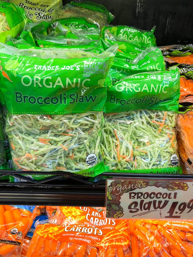 Multiple bags of organic broccoli slaw on a shelf at Trader Joe's. 