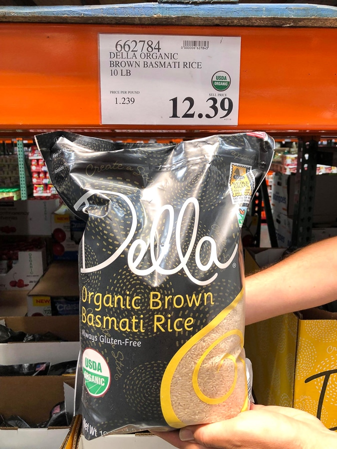 A hand holding a bag of organic vegan brown basmati rice for $12.39 at Costco. 