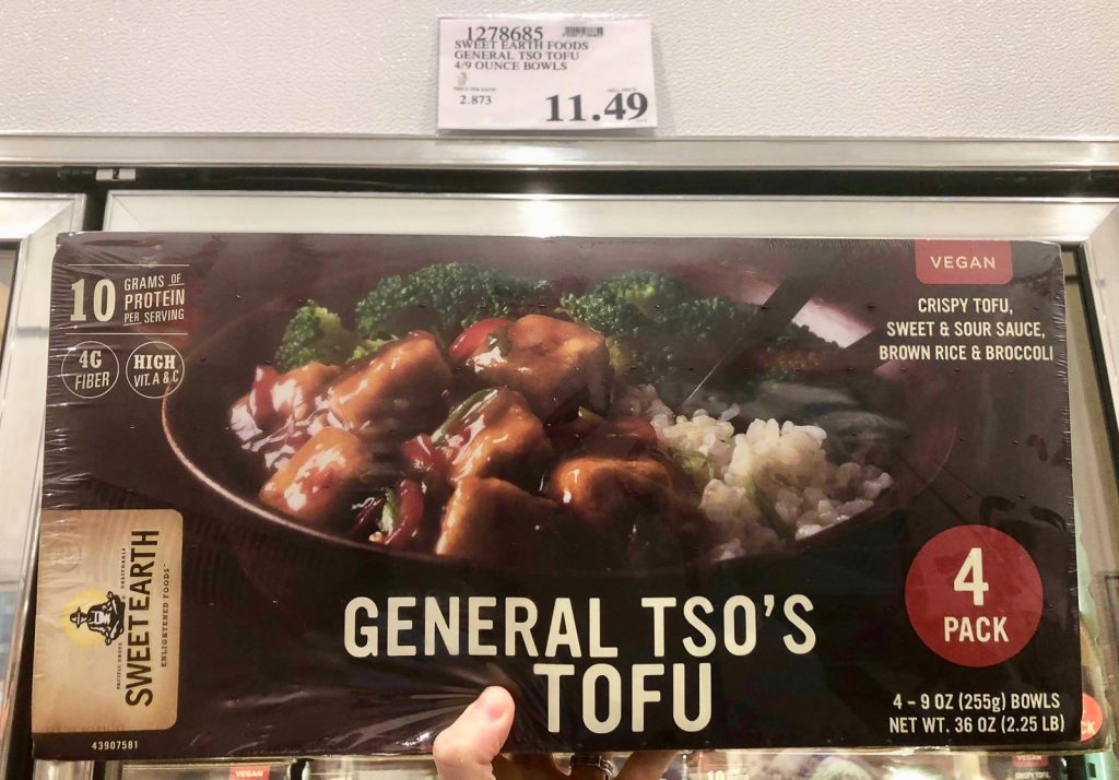 A hand holding a box of general so's tofu for $11.49 at Costco.