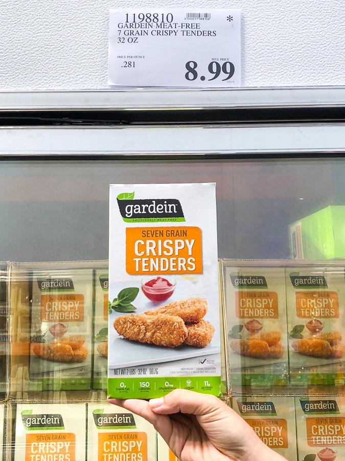 A hand holding a box of frozen organic vegan gardein tenders for $8.99 at Costco.