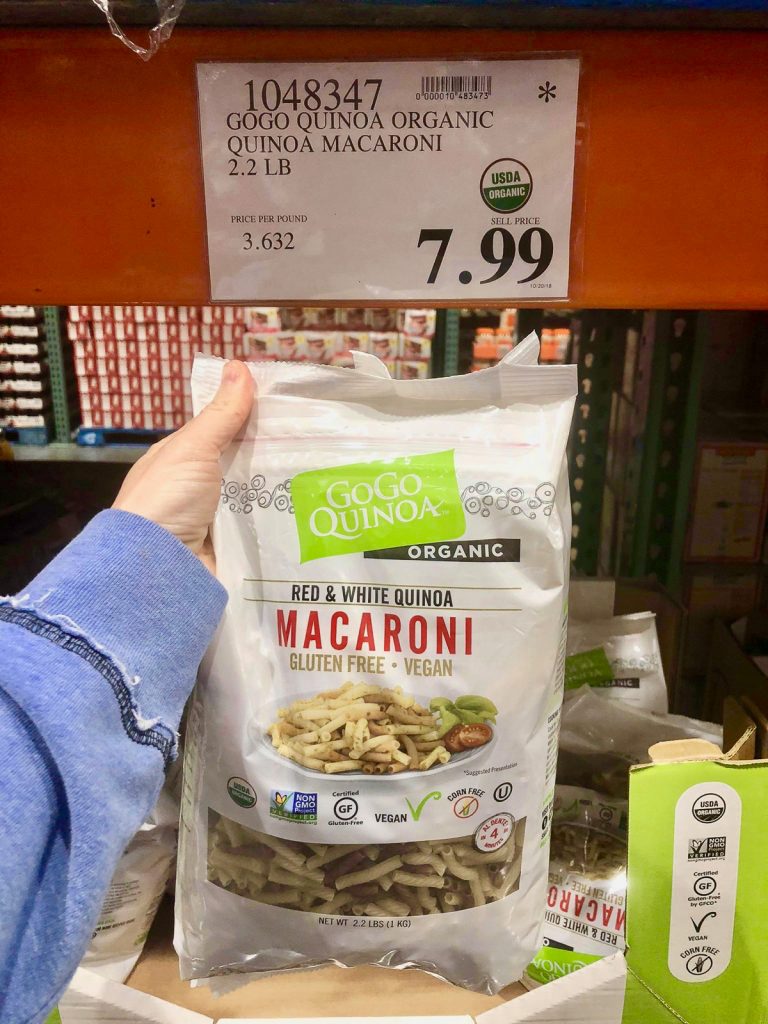 A hand holding a bag of GoGo Quinoa macaroni for $7.99 at Costco. 