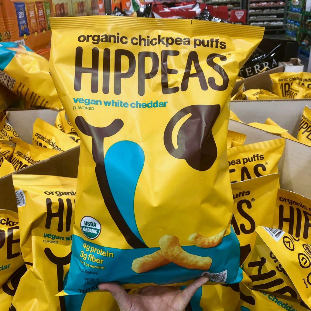 A hand holding a large bag of organic vegan hippeas at Costco.
