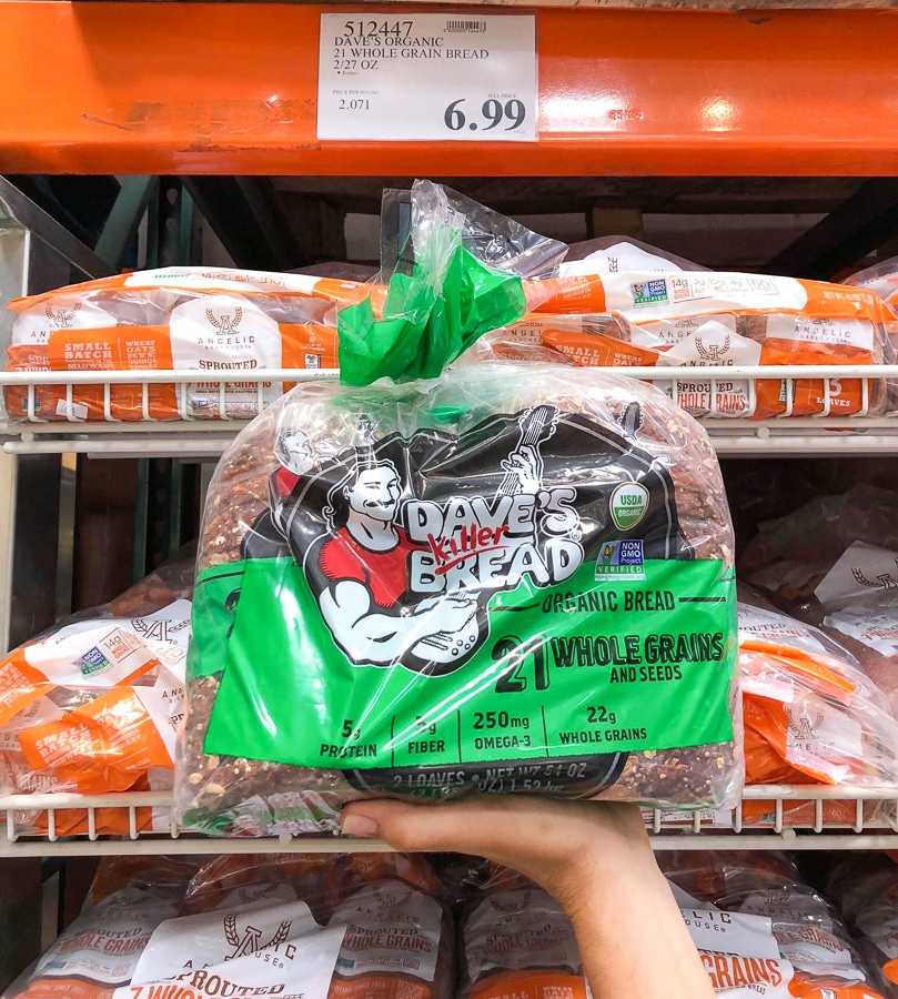 A hand holding a bag of 2 loaves of organic vegan bread at Costco.