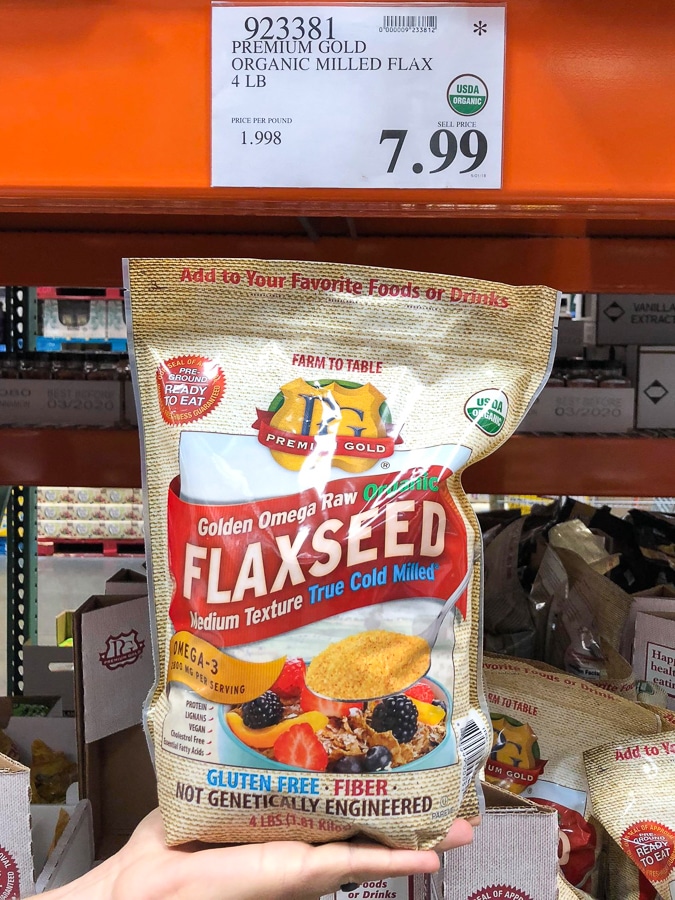 A hand holding a large bag of organic vegan flaxseed for $7.99 at Costco.