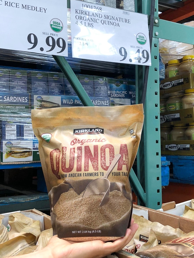 A hand holding a bag of organic vegan quinoa for $9.49 at Costco. 