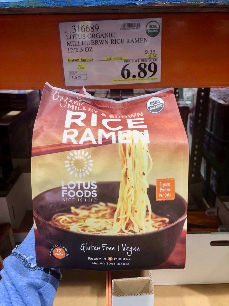 A hand holding a bag of organic vegan rice ramen noodles packets for $6.89 at Costco. 