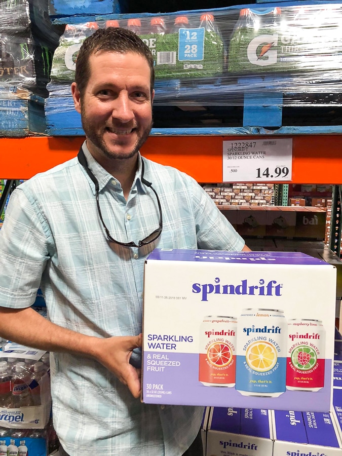 A man holding a large box of Spindrift soda for $14.99 at Costco.