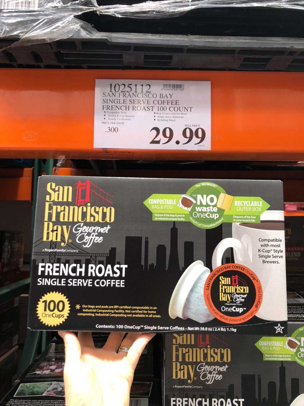 A hand holding a large box of San Francisco Bay no waste cups for $29.99 at Costco.