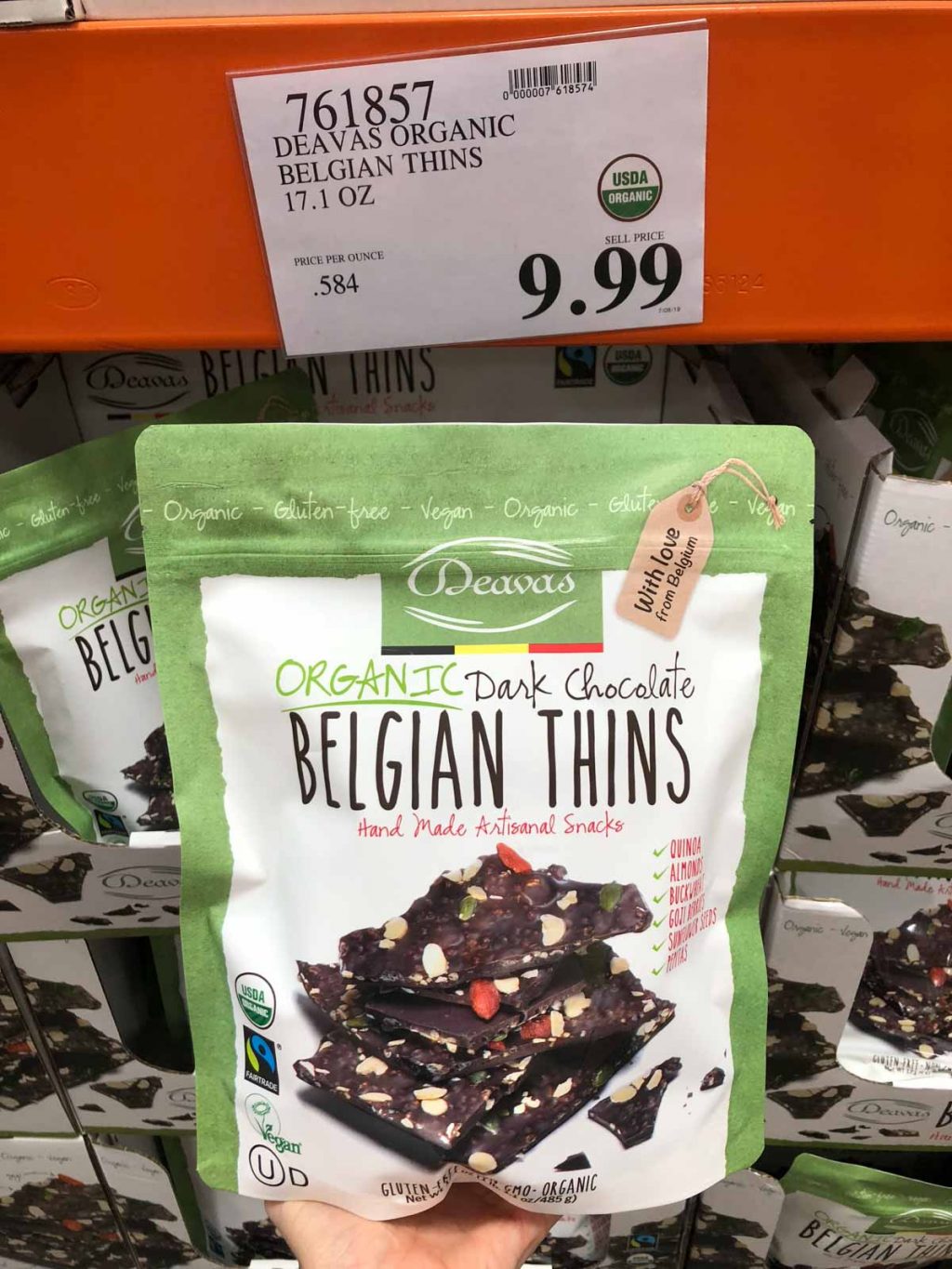 A hand holding a bag of organic vegan dark chocolate thins for $9.99 at Costco