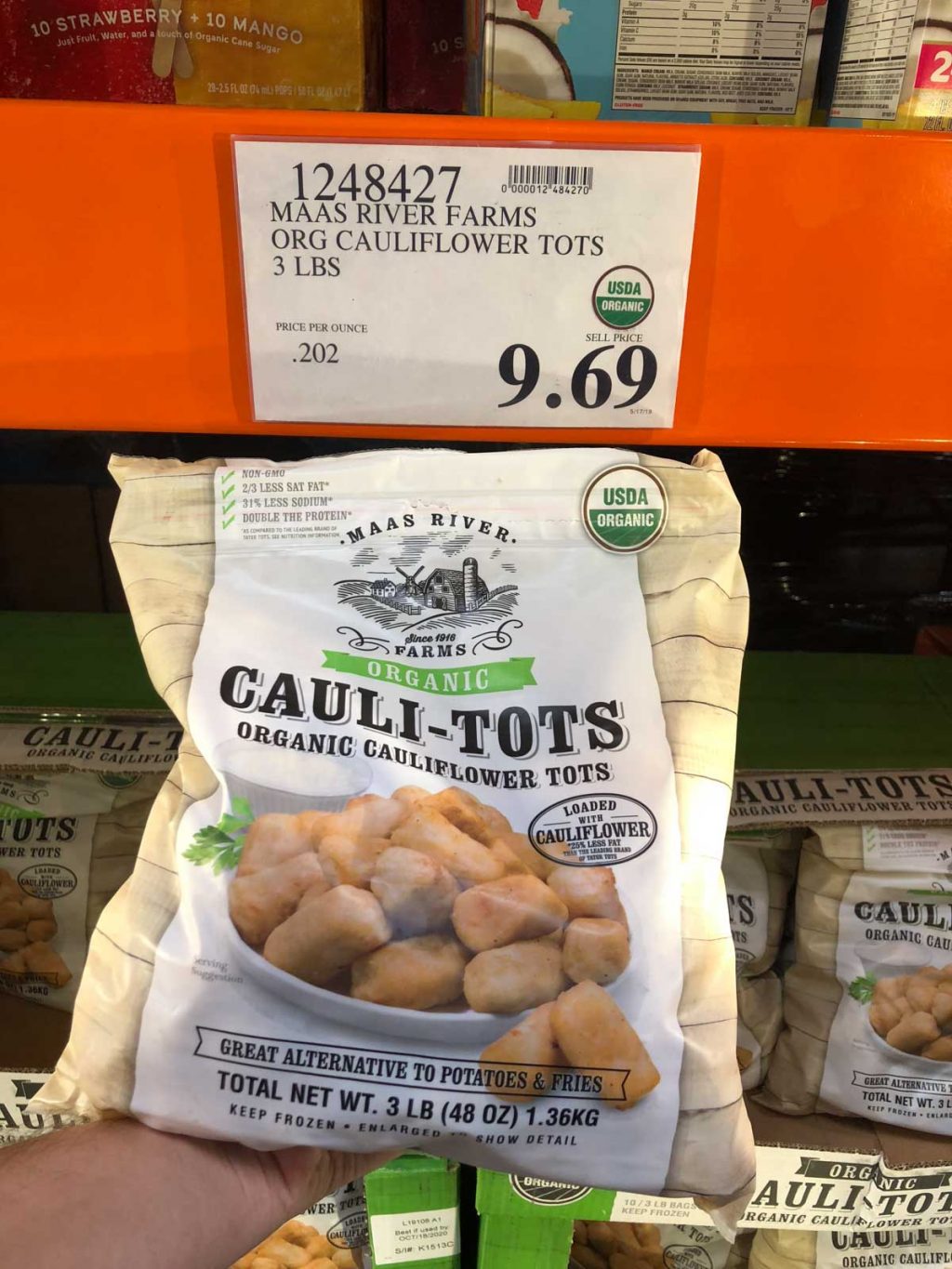 A hand holding a bag of frozen organic vegan cauliflower tots for $9.69 at Costco.