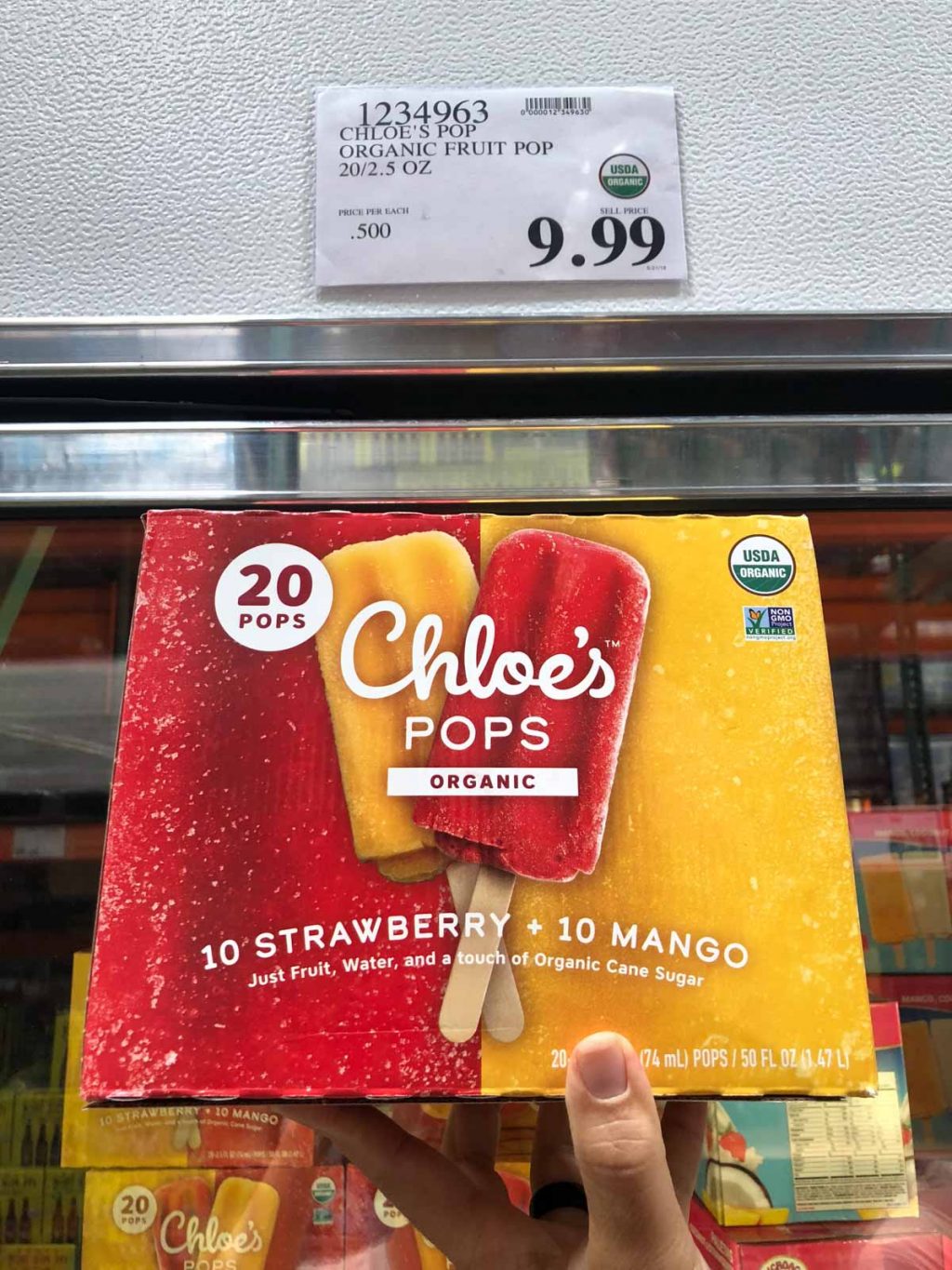 A hand holding a box of Chloe's organic vegan pops for $9.99 at Costco. 