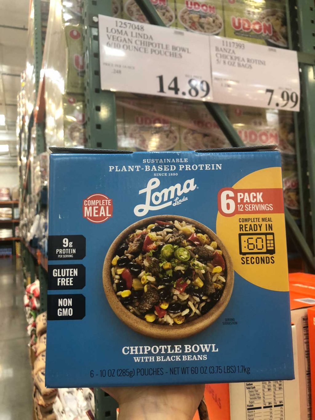 A hand holding a blue box of Loma Linda plant-based protein bowls for $14.89 at Costco.