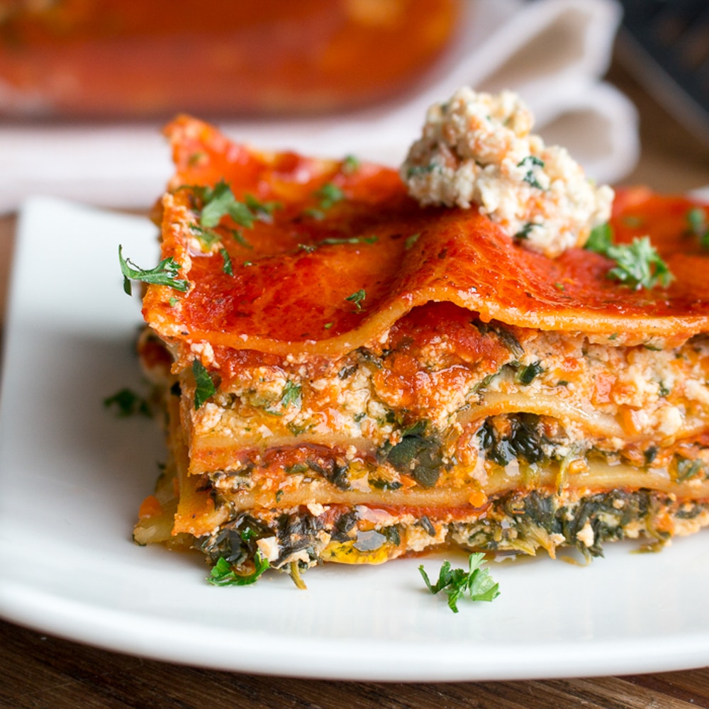 A large slice of vegan lasagna with tofu ricotta on a white plate. 