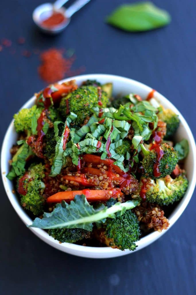 A white bowl of broccoli quinoa fried rice on a dark background. 