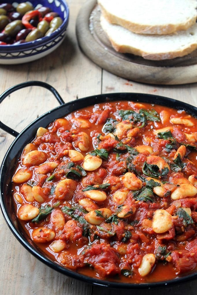 A large skillet of tomato and bean stew on a rustic background. 