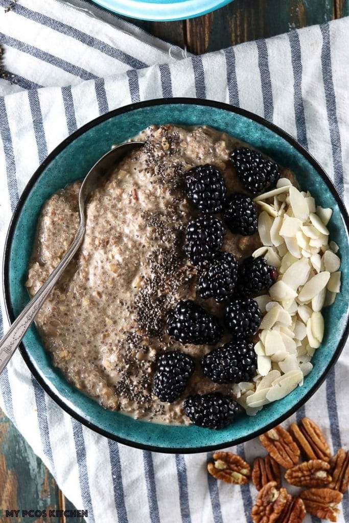 A low-carb vegan keto breakfast bowl of oatmeal (no oats) that's topped with blackberries and sliced almonds and it's sitting on a stripped white towel.