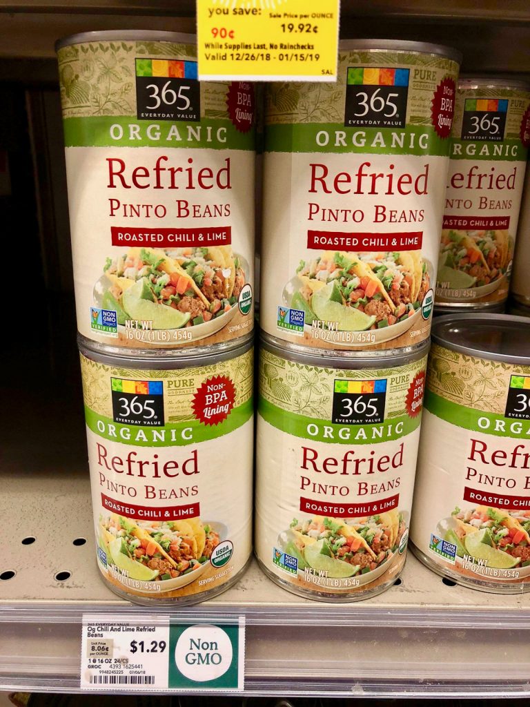 Multiple cans of organic refried beans on a shelf at Whole Foods. 