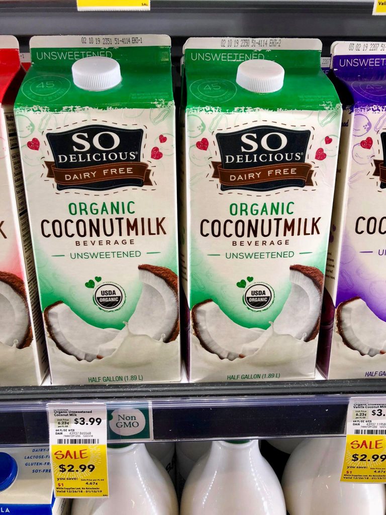 Two containers of So Delicious unsweetened coconut milk on a shelf at Whole Foods. 