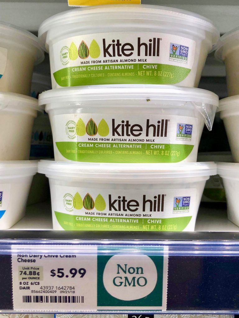 Three tubs of Kite Hill vegan cream cheese on a shelf at Whole Foods. 