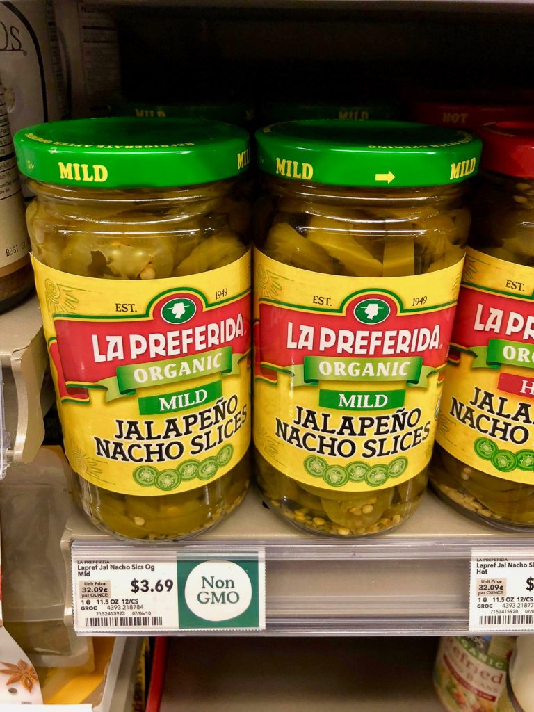 Two bottles of organic jalapeño slices on a shelf at Whole Foods. 