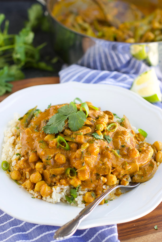 A white plate filled with vegan chickpea curry next to a blue napkin.