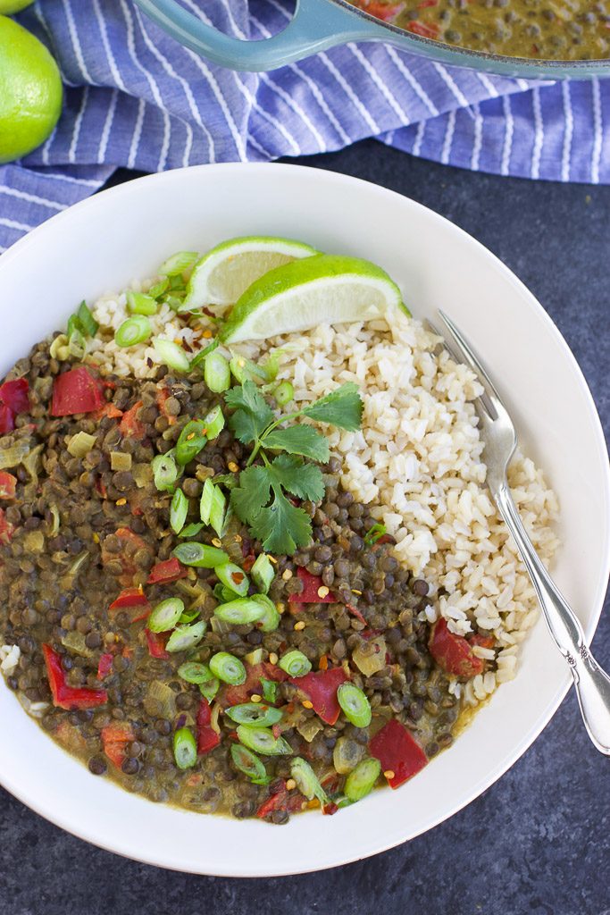 A white bowl filled with curried lentils and rice on a blue texture background. 