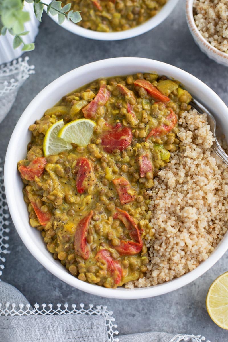 A white bowl filled with quinoa and lentils on a gray background. 