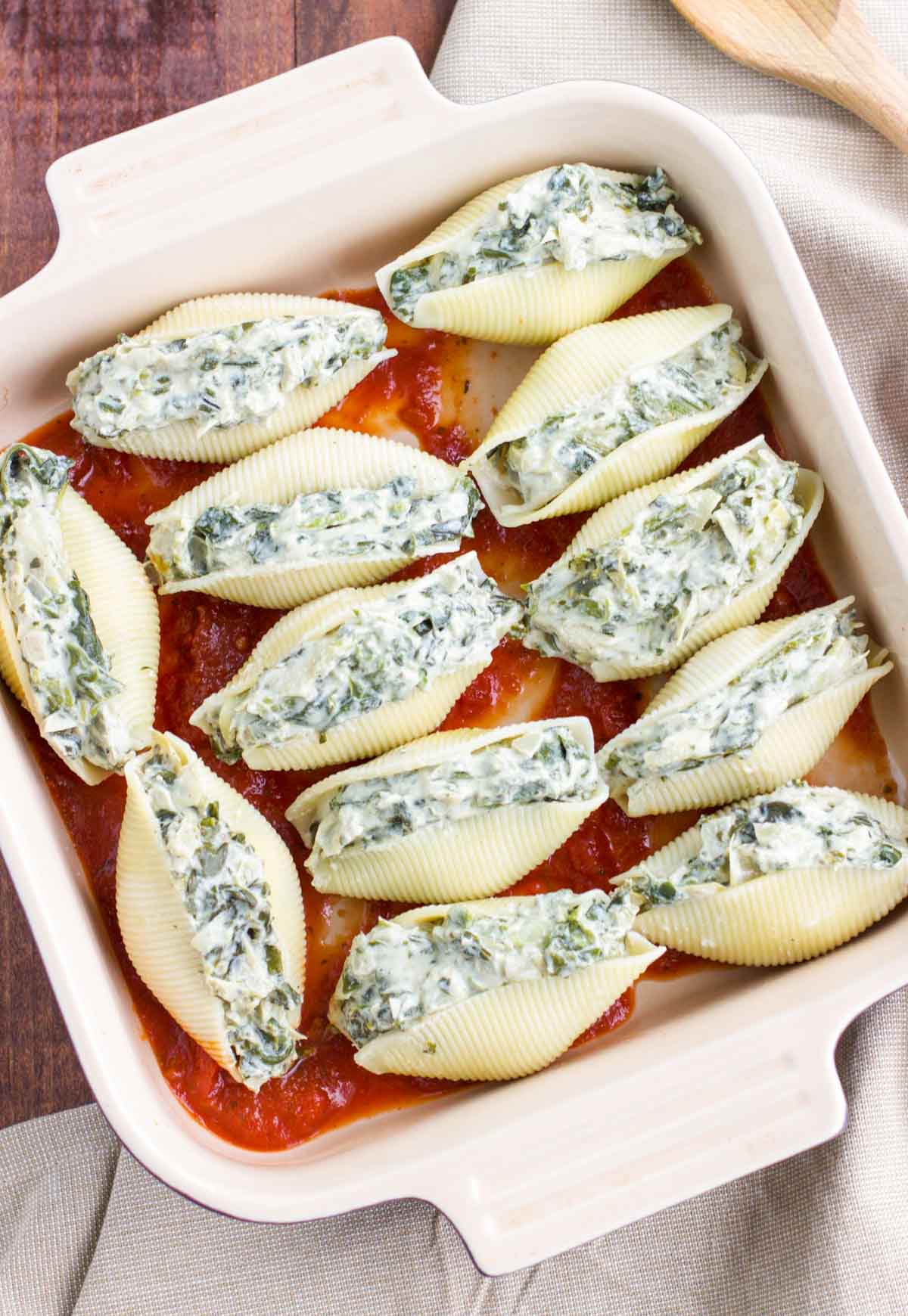 Overhead shot of a casserole dish filled with stuffed shells without sauce on a rustic background.