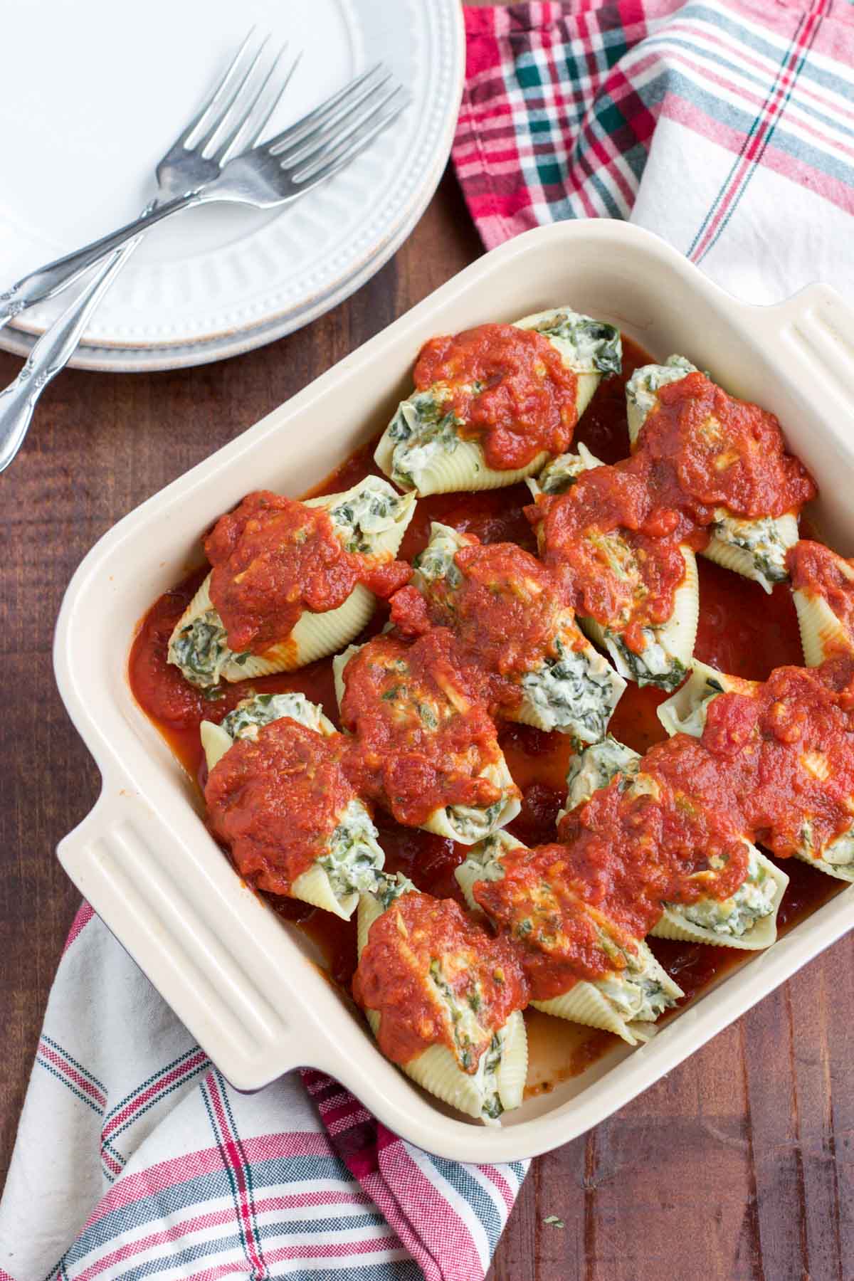 Overhead shot of a casserole dish filled with vegan stuffed shells on top of a plaid towel. 