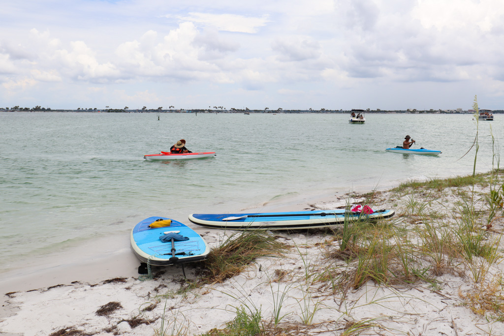 People kayaking in the water to the shore on Caladesi Island beach.