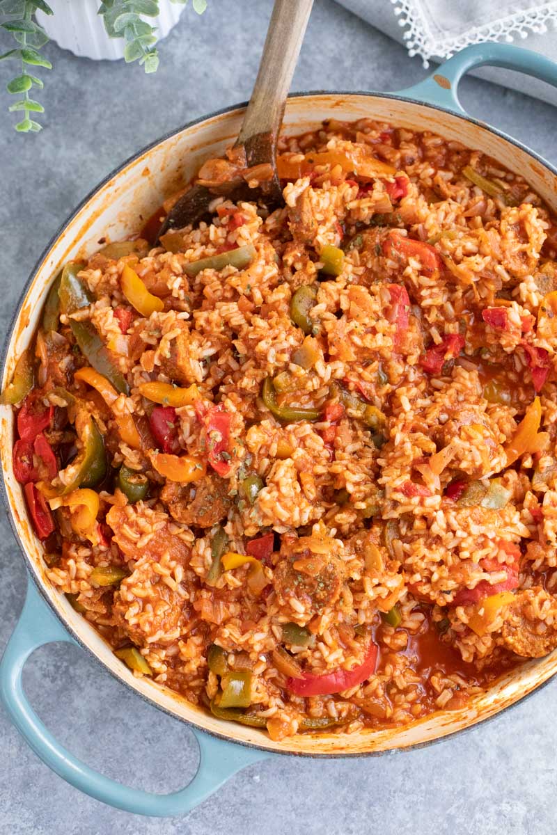 A large blue pan filled with vegan sausage, peppers, and rice on a gray background. 