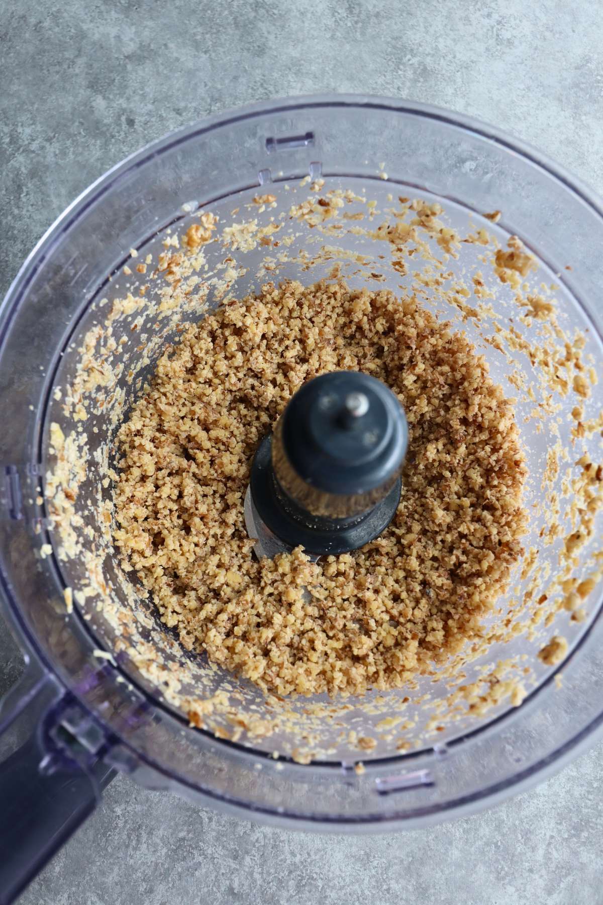 A food processor cup filled with chopped walnuts. 