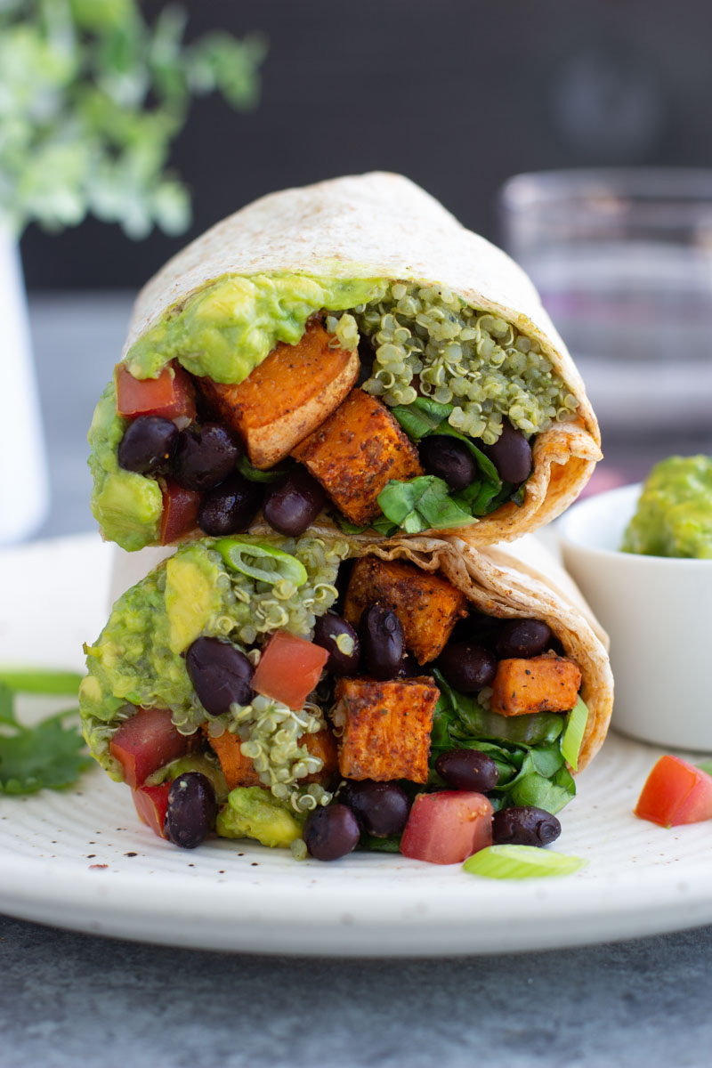 A close up view of two halves of a vegan burrito stacked on top of each other. 