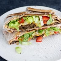 A vegan crunchwrap supreme on a white plate.