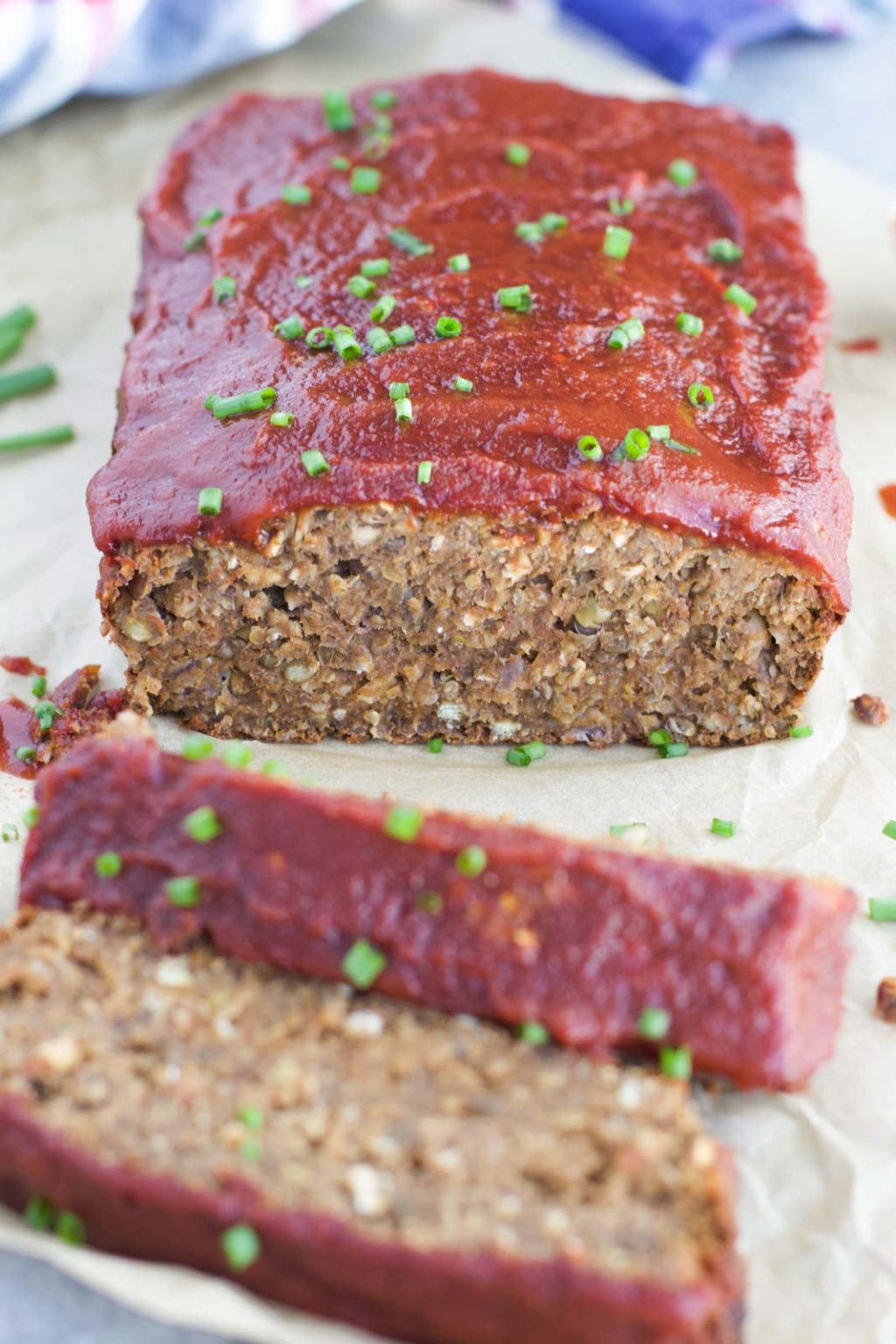 Vegan meatloaf being cut into wedges on top of a piece of parchment paper. 