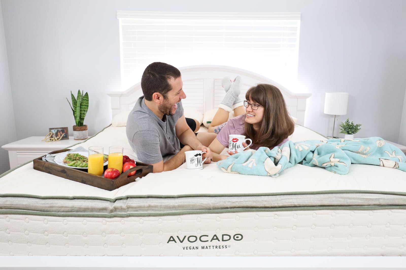 A smiling man and women laying on a bed and laughing at each other.