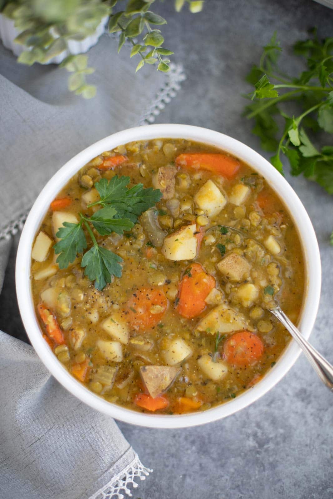 A white bowl filled with vegan split pea soup on a gray background. 