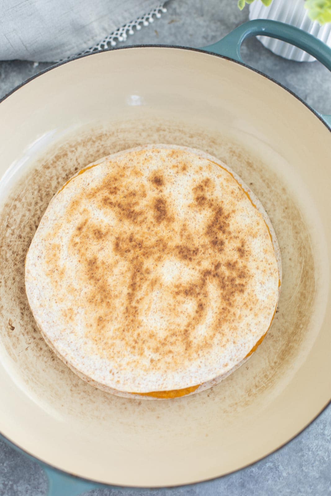 A hummus quesadilla in a large pan on a gray background.