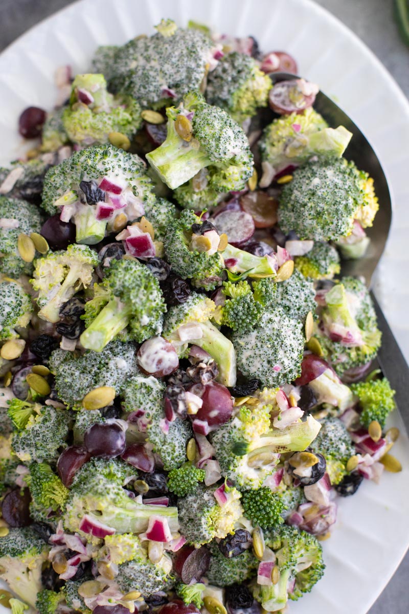 A white platter filled with broccoli salad and a serving spoon.