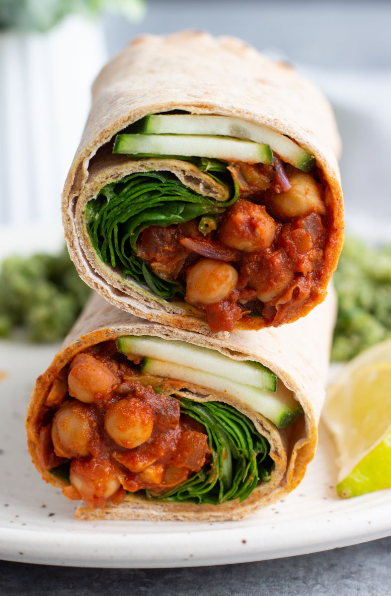 Close up view of two halves of a wrap stacked on top of each other on a white plate. 