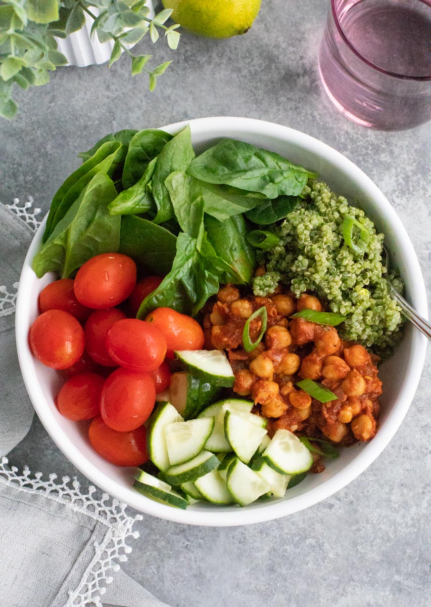 A white bowl filled with vegetables and smoky chickpeas on a gray background. 