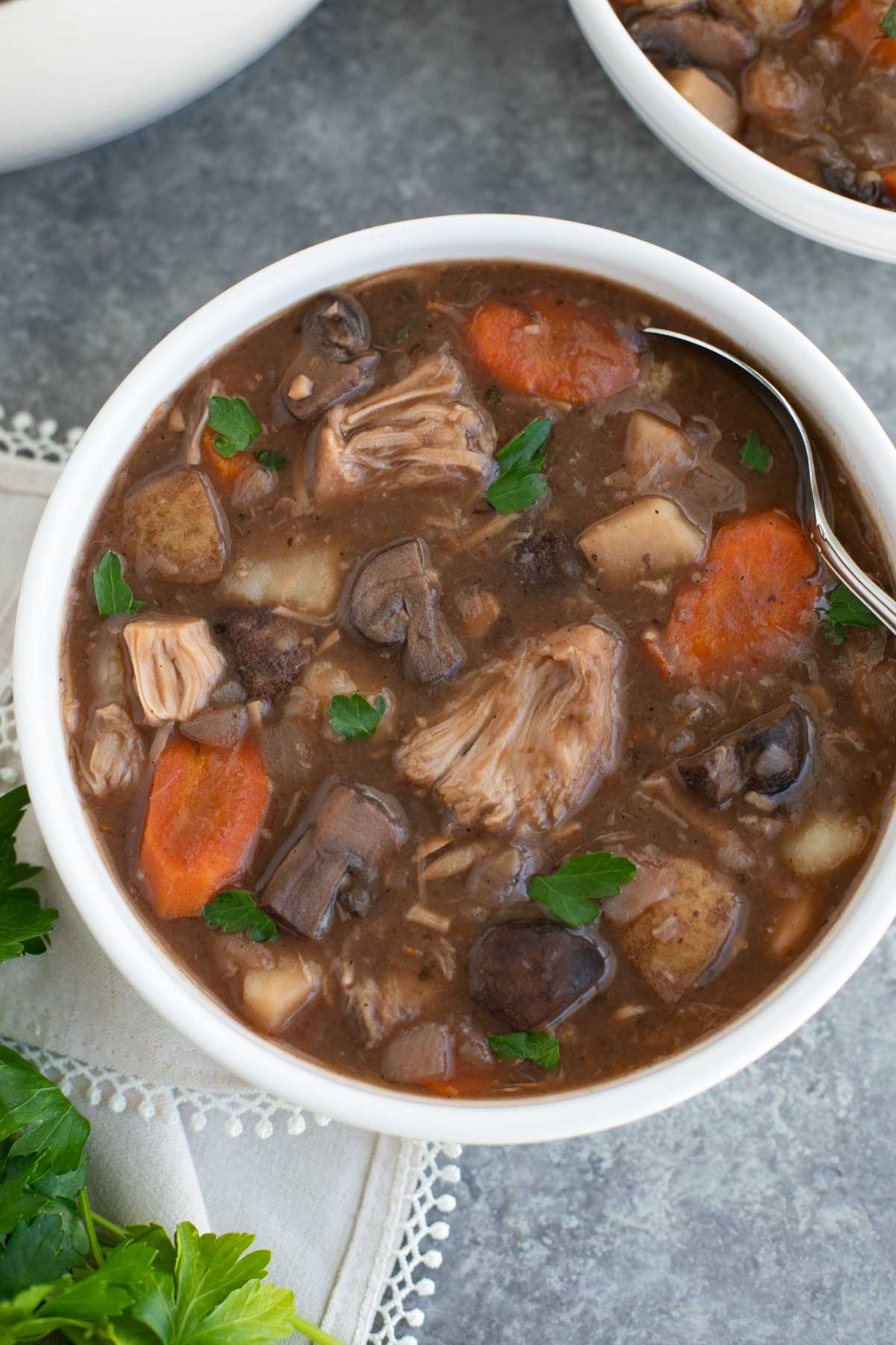 A white bowl filled with beetles stew and a spoon on a gray background.